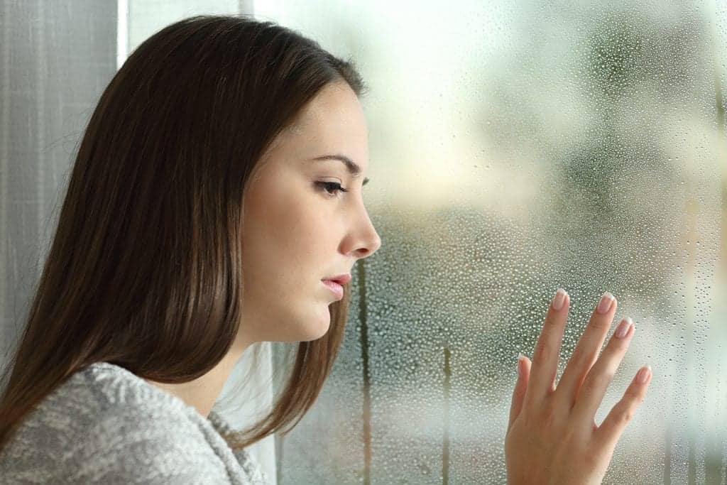 Depressed woman staring out of a window mental health condition