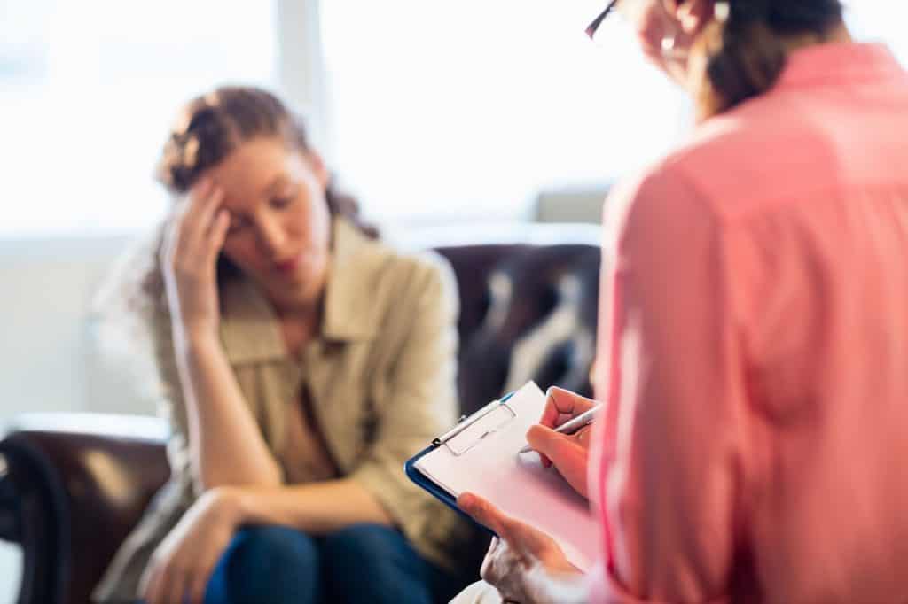 Distressed young woman speaking with a therapist