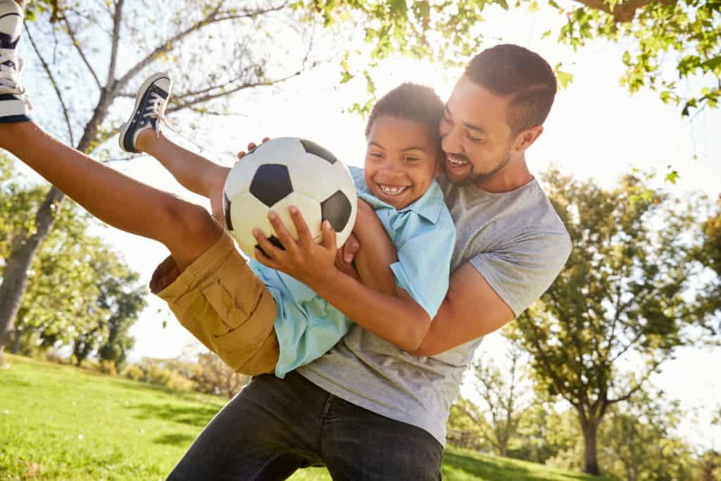 Father and son playing soccer in a park traditional masculinity