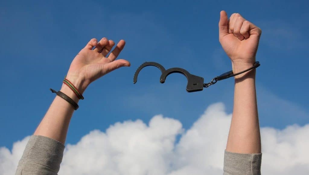 Pair of hands up in the air with broken handcuffs addiction recovery