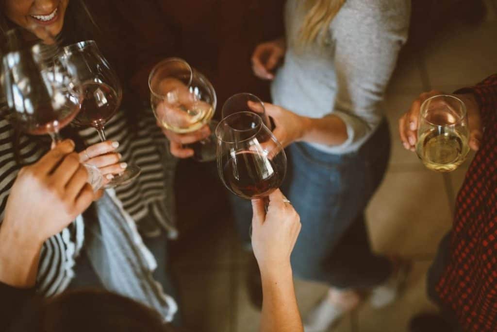 Several people holding wine glasses romanticizing alcoholism