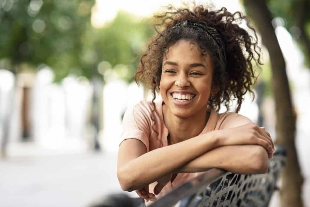 Portrait of happy young woman sitting on a bench
