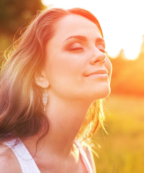Young woman in a field enjoying the sunshine
