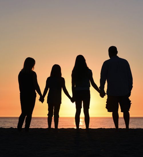 4 people holding hands at the beach at sunset