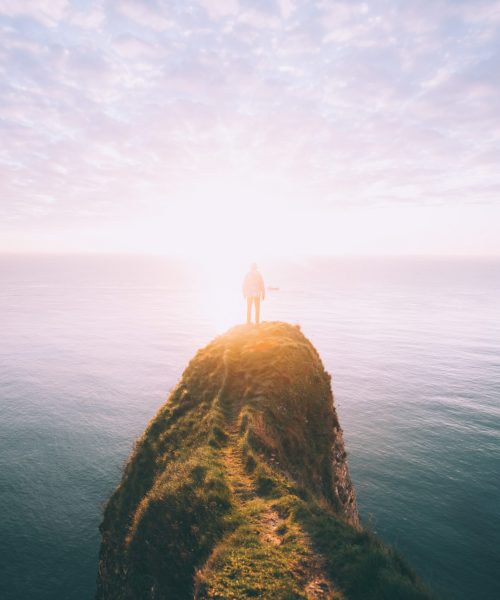 Man at the edge of a rocky point overlooking the ocean